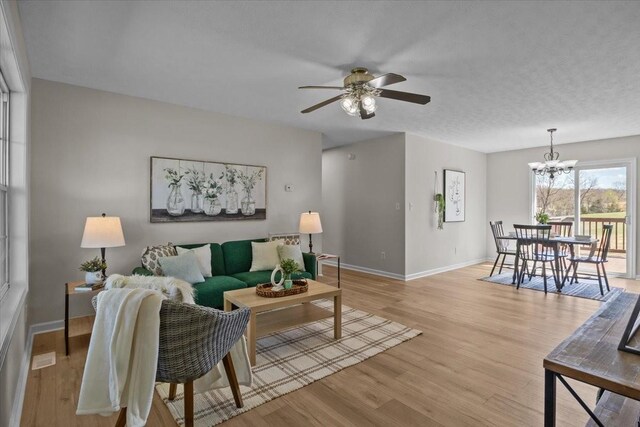 650 Wall Rd, Cunningham, TN 37052 - living area with baseboards, a textured ceiling, light wood-type flooring, and ceiling fan with notable chandelier