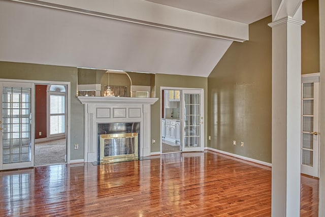 unfurnished living room with baseboards, vaulted ceiling with beams, wood finished floors, and a fireplace