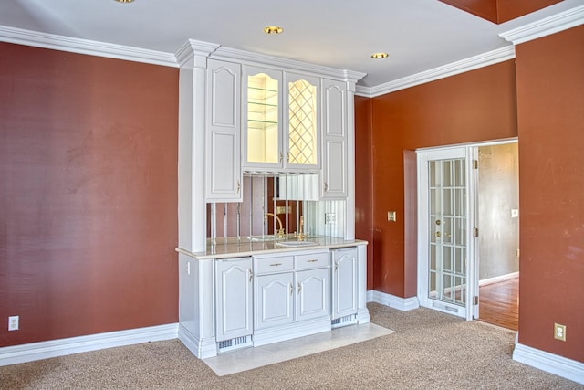 bar with light colored carpet, baseboards, ornamental molding, and a sink
