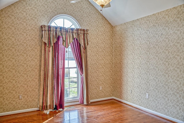 empty room featuring hardwood / wood-style floors, wallpapered walls, and a ceiling fan