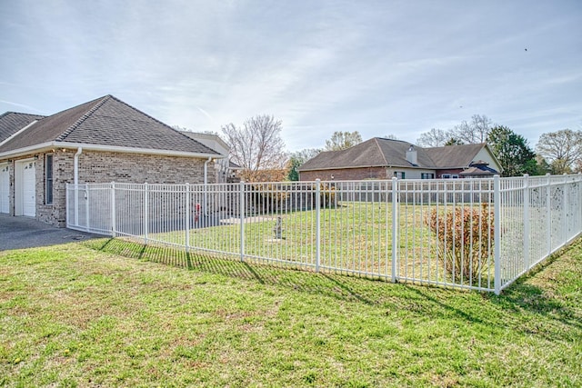 view of yard with driveway, a garage, and fence