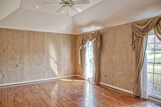 empty room featuring visible vents, baseboards, ceiling fan, lofted ceiling, and hardwood / wood-style floors