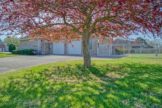 view of yard with driveway, an attached garage, and fence