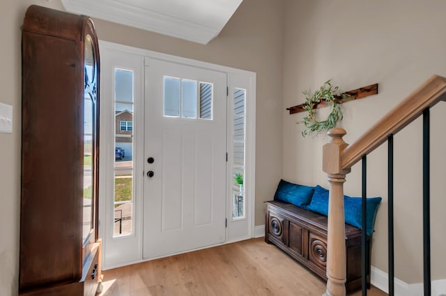 foyer entrance with stairs, ornamental molding, and light wood-type flooring