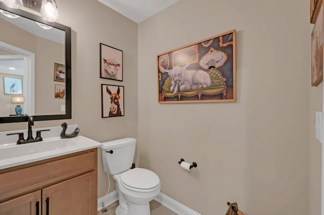 half bath featuring baseboards, toilet, and vanity