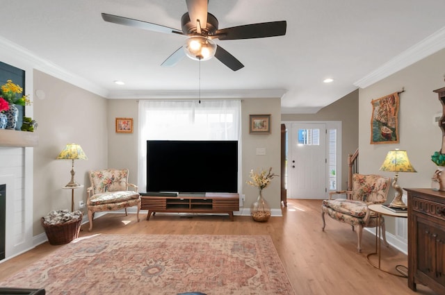 living area featuring ornamental molding, baseboards, light wood finished floors, ceiling fan, and a fireplace