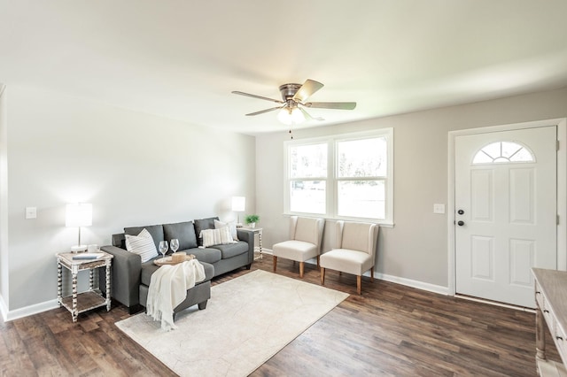 living room with baseboards, a ceiling fan, and dark wood-style flooring