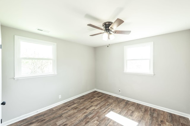 empty room with baseboards, visible vents, ceiling fan, and dark wood-type flooring
