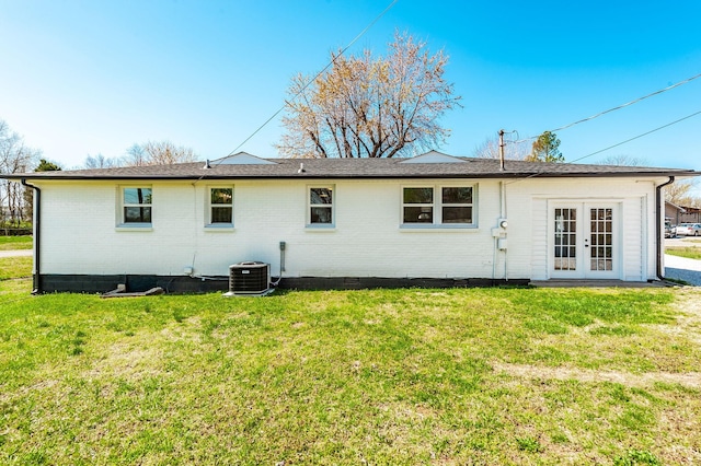 back of house featuring brick siding, cooling unit, french doors, and a lawn