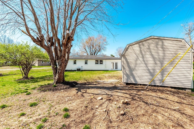 rear view of house with an outbuilding, a storage unit, and a lawn