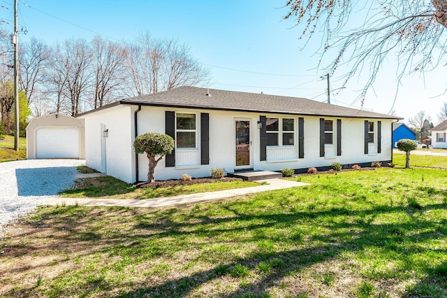 ranch-style home with an outbuilding, a front lawn, a shingled roof, gravel driveway, and a garage