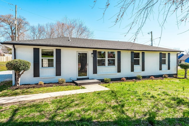 ranch-style house with brick siding, roof with shingles, and a front lawn