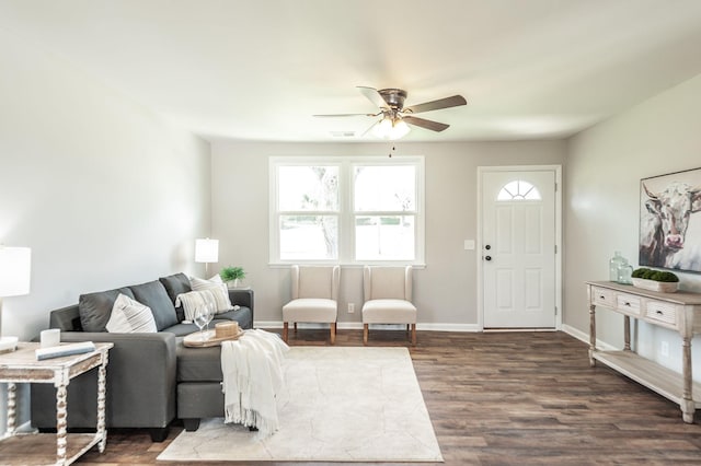 living area featuring dark wood-type flooring, visible vents, baseboards, and a ceiling fan