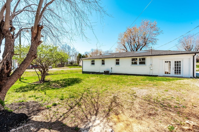 rear view of house with french doors, cooling unit, and a lawn