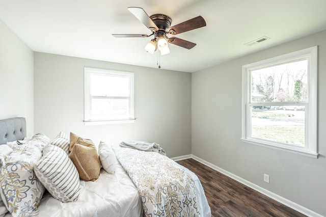 bedroom featuring baseboards, visible vents, a ceiling fan, and dark wood-style flooring