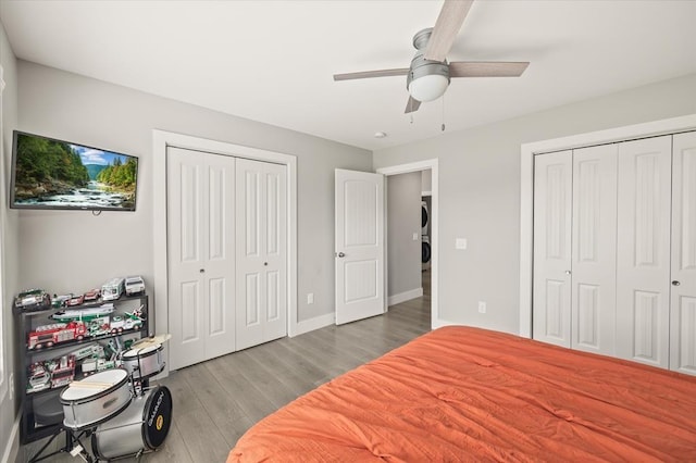 bedroom featuring baseboards, wood finished floors, two closets, and a ceiling fan