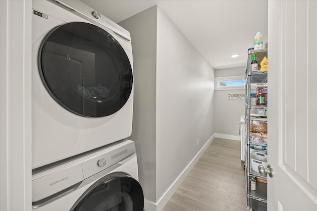 laundry area featuring recessed lighting, baseboards, light wood-style floors, stacked washer / dryer, and laundry area
