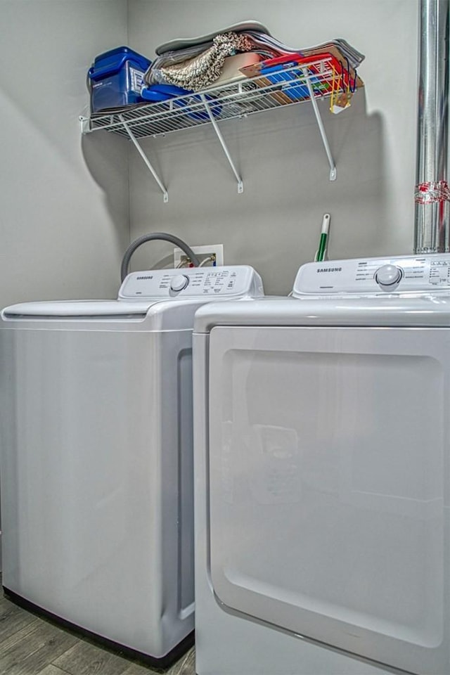 clothes washing area with wood finished floors, laundry area, and separate washer and dryer