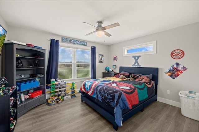 bedroom featuring baseboards, ceiling fan, wood finished floors, and multiple windows