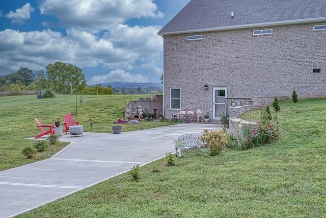 exterior space with a lawn, brick siding, concrete driveway, and a patio area