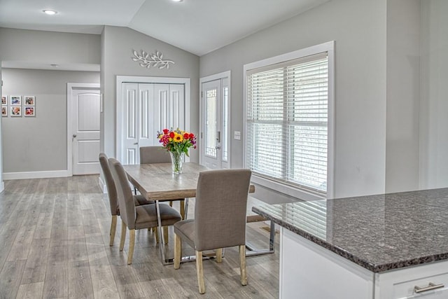 dining space featuring baseboards, vaulted ceiling, and light wood-type flooring