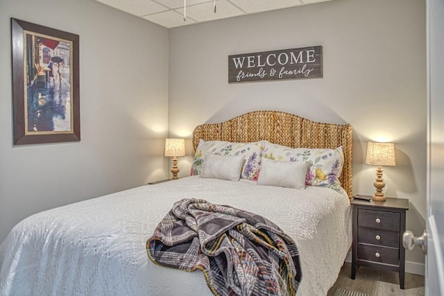 bedroom featuring a drop ceiling and wood finished floors