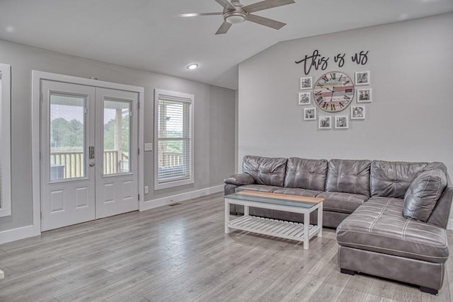 living room with light wood-type flooring, a ceiling fan, french doors, and vaulted ceiling
