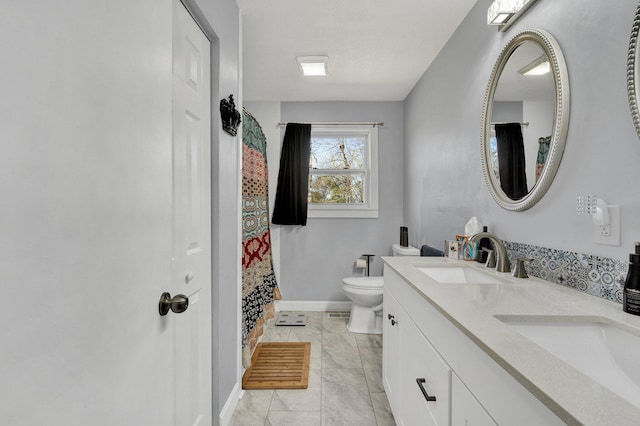 bathroom with toilet, a sink, double vanity, and baseboards