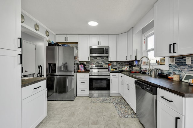 kitchen with white cabinets, a sink, tasteful backsplash, and appliances with stainless steel finishes