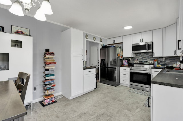 kitchen with dark countertops, white cabinets, backsplash, and stainless steel appliances