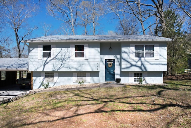 split foyer home featuring a front yard, an attached carport, and metal roof
