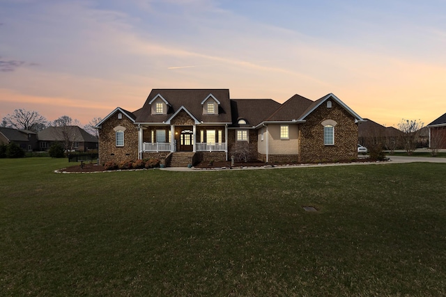 view of front facade with crawl space, brick siding, a shingled roof, a lawn, and a porch