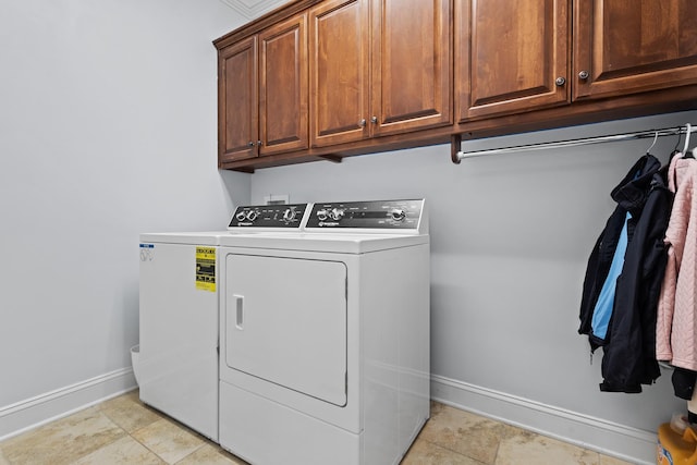 clothes washing area featuring washing machine and clothes dryer, cabinet space, and baseboards