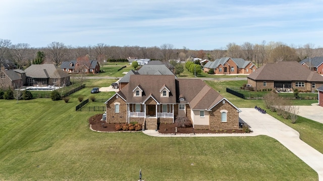 view of front of property with a front yard, concrete driveway, brick siding, a residential view, and a porch