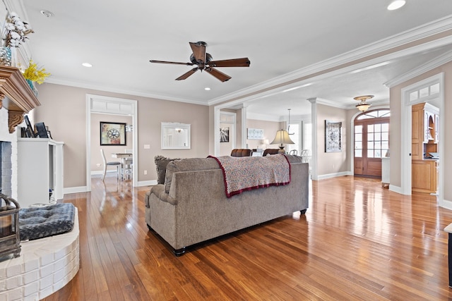 living room featuring ornamental molding, hardwood / wood-style flooring, baseboards, and ceiling fan