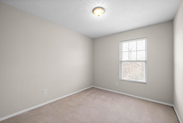 unfurnished room with light carpet, baseboards, and a textured ceiling