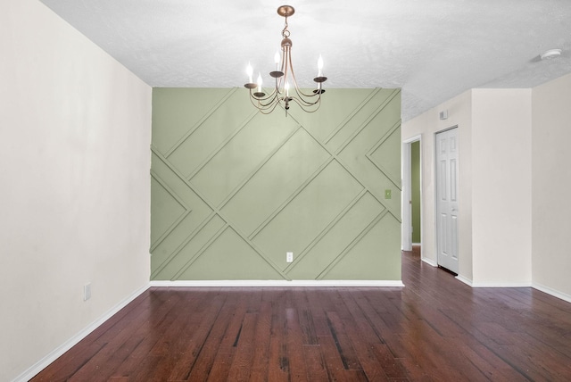 unfurnished dining area featuring baseboards, wood finished floors, and a notable chandelier