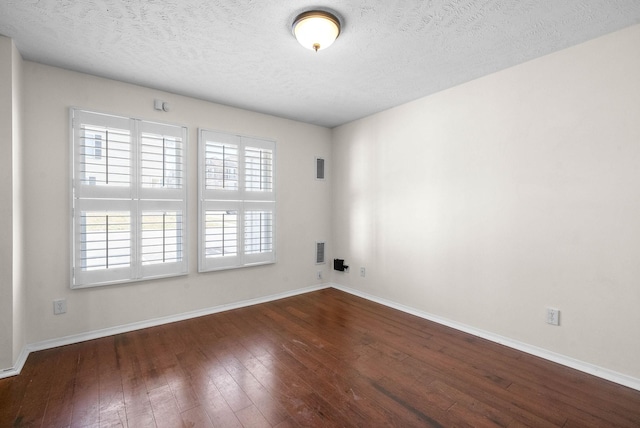 empty room featuring dark wood finished floors, baseboards, and a textured ceiling