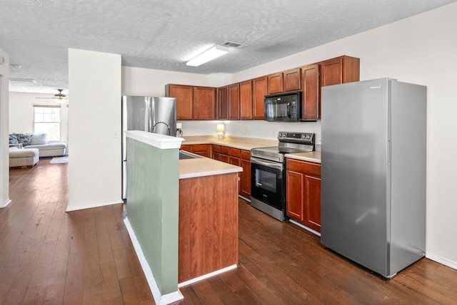kitchen with light countertops, visible vents, a kitchen island with sink, appliances with stainless steel finishes, and dark wood-style floors