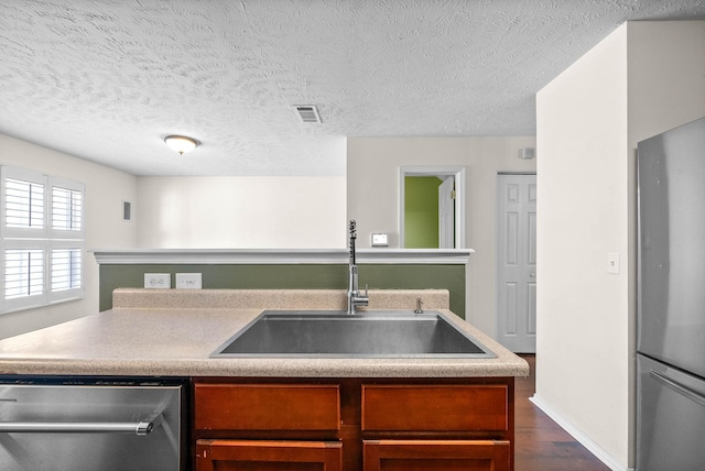 kitchen with dark wood-style flooring, light countertops, visible vents, appliances with stainless steel finishes, and a sink