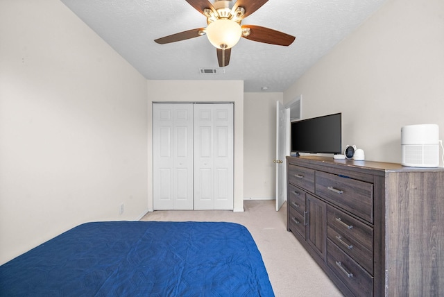 bedroom featuring a textured ceiling, visible vents, a ceiling fan, and light colored carpet