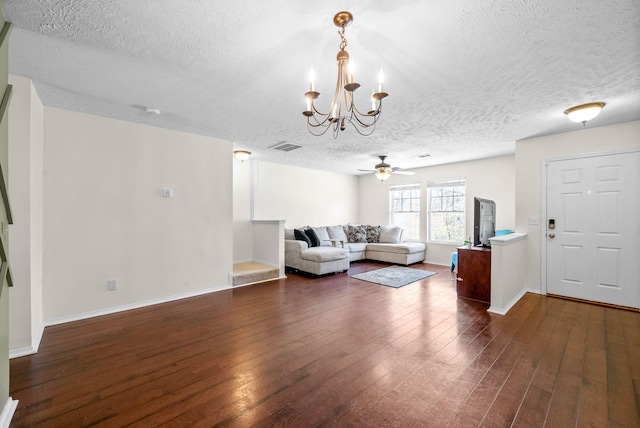 unfurnished living room featuring ceiling fan with notable chandelier, dark wood-style floors, baseboards, and a textured ceiling