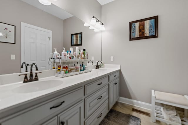 bathroom with double vanity, visible vents, baseboards, and a sink