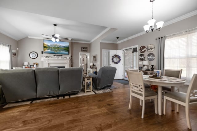 dining area with crown molding, a fireplace, wood finished floors, ceiling fan with notable chandelier, and vaulted ceiling