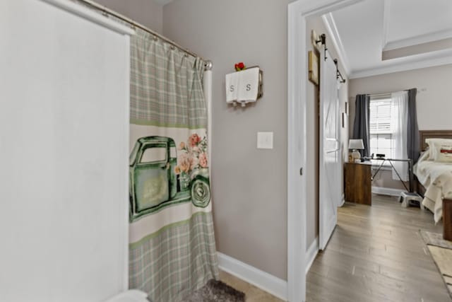 full bath with a shower with curtain, ornamental molding, baseboards, a raised ceiling, and wood finished floors
