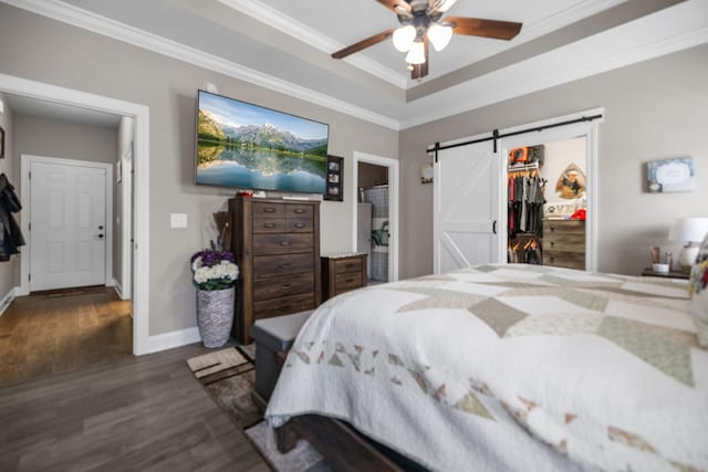 bedroom with crown molding, a barn door, wood finished floors, and a spacious closet