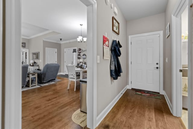 entryway featuring baseboards, wood finished floors, a chandelier, and crown molding