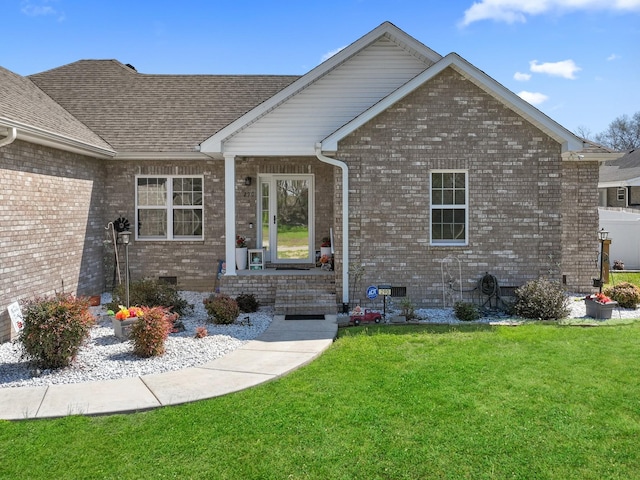 doorway to property with crawl space, a shingled roof, brick siding, and a yard