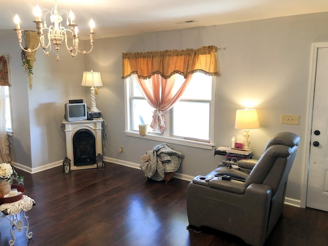 living area with a notable chandelier, a fireplace, wood finished floors, baseboards, and visible vents