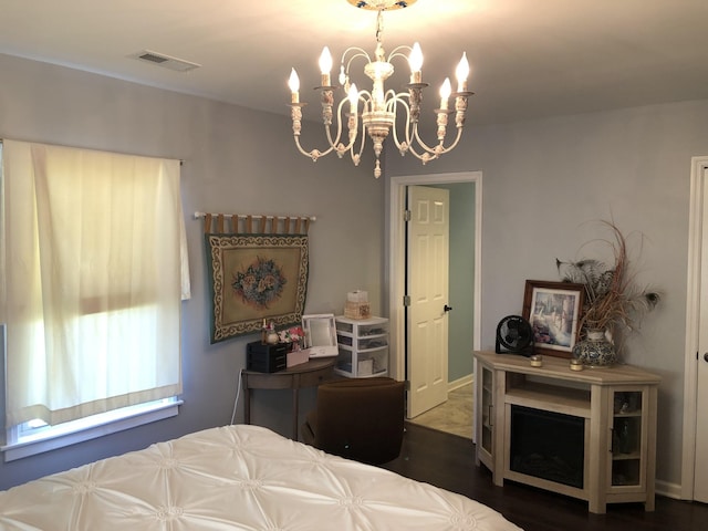 bedroom with visible vents, a notable chandelier, and wood finished floors